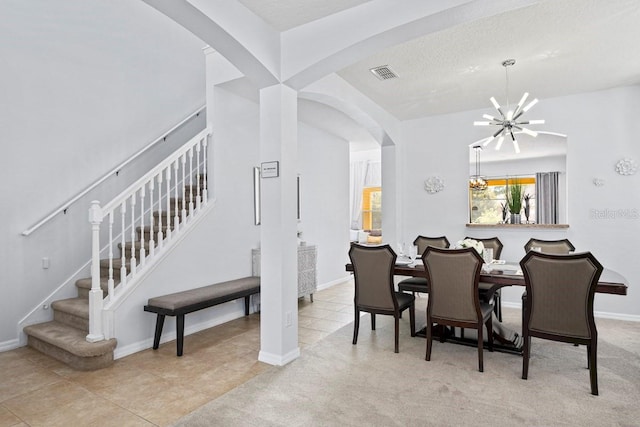 carpeted dining room featuring tile patterned floors, visible vents, a notable chandelier, arched walkways, and stairs