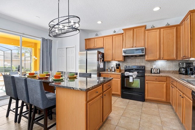 kitchen featuring black appliances, dark stone countertops, a sink, a center island, and decorative backsplash