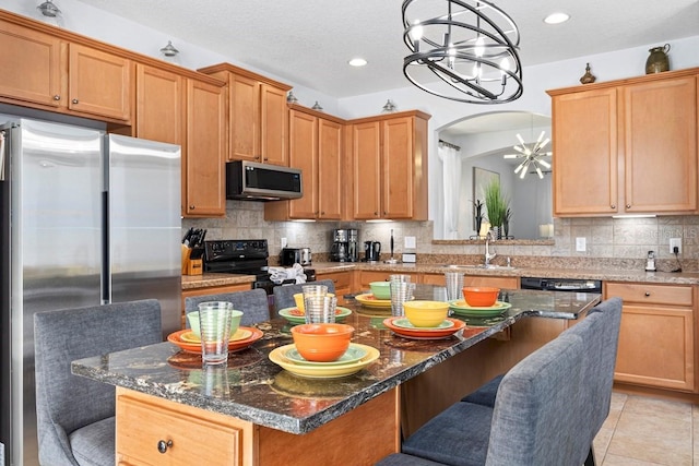 kitchen featuring a sink, black appliances, a chandelier, and a breakfast bar