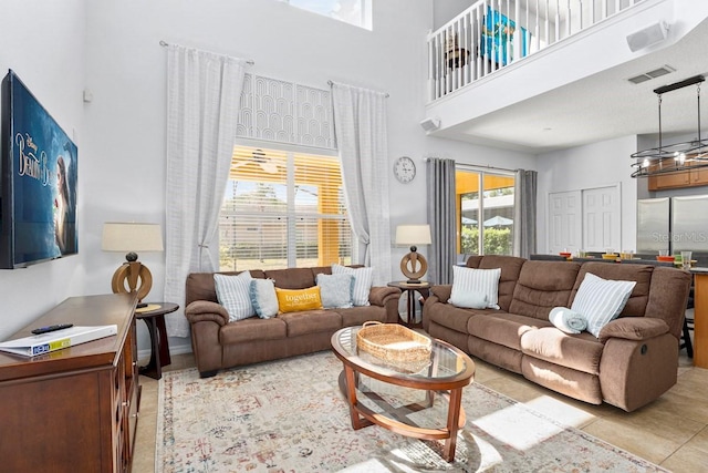 living room with light tile patterned floors, visible vents, and a towering ceiling