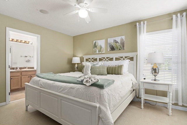 bedroom with light colored carpet, ensuite bathroom, ceiling fan, and a sink