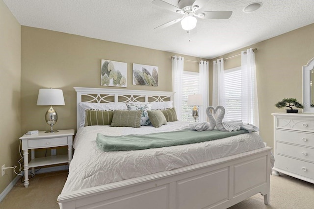 bedroom featuring light colored carpet, a textured ceiling, and ceiling fan