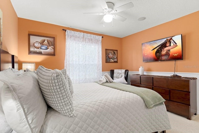 bedroom with a wainscoted wall, carpet floors, and a ceiling fan