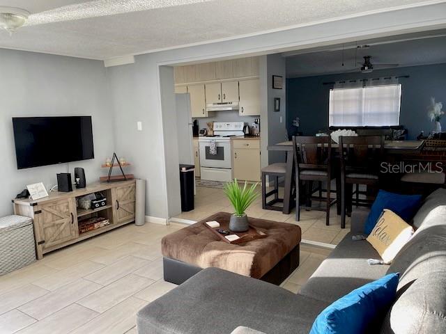 living area with ceiling fan, baseboards, and a textured ceiling