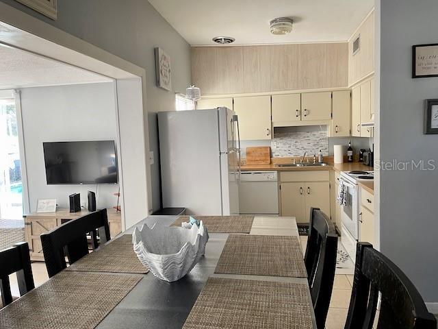 kitchen featuring visible vents, a sink, tasteful backsplash, white appliances, and light countertops