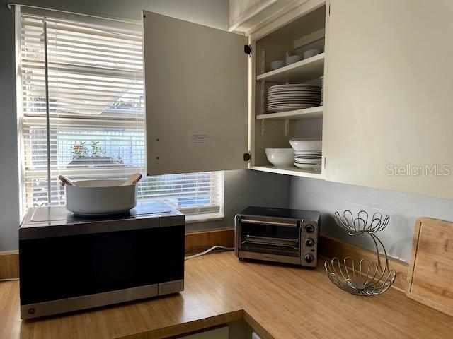 interior details with stainless steel microwave, wood finished floors, and a toaster