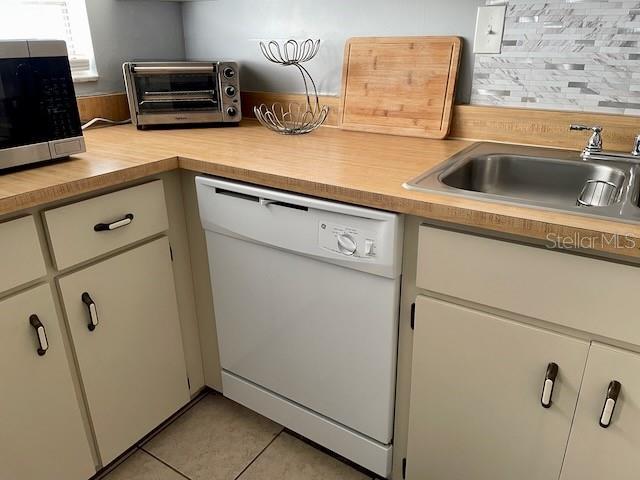 kitchen with a toaster, white dishwasher, a sink, light countertops, and stainless steel microwave