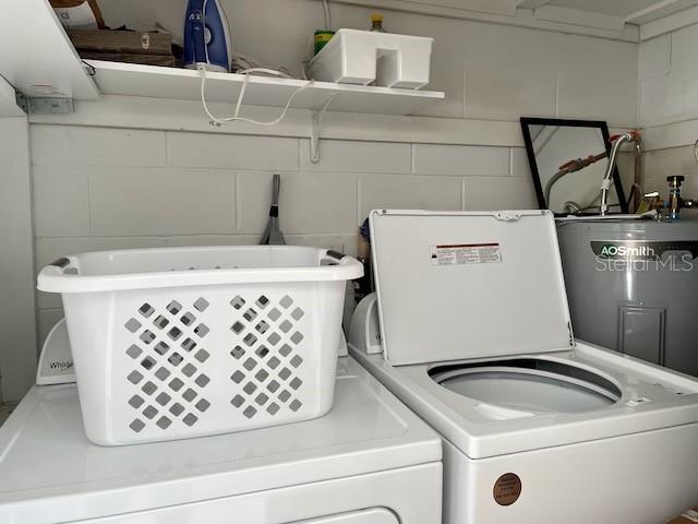 washroom with washing machine and dryer, water heater, and laundry area