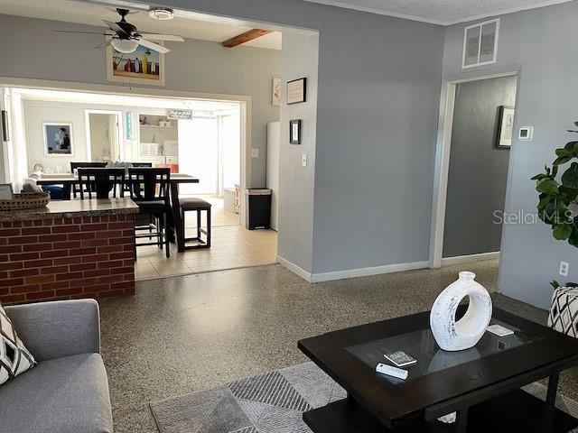 living room featuring baseboards, visible vents, light speckled floor, and ceiling fan