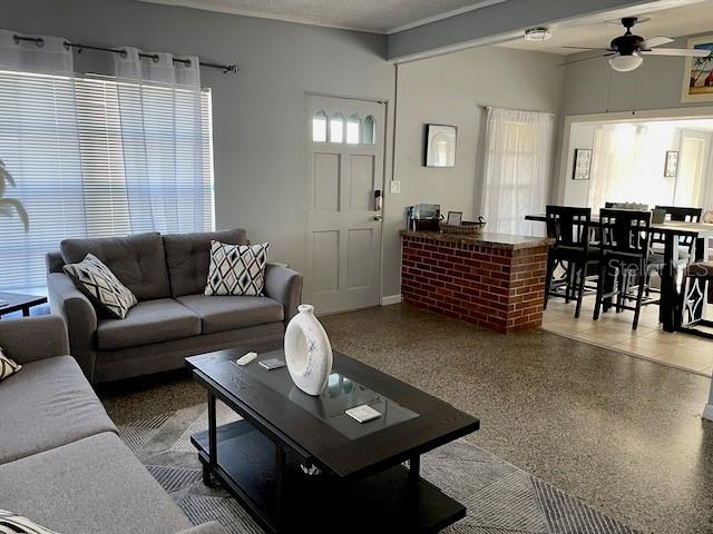 living area with speckled floor and ceiling fan