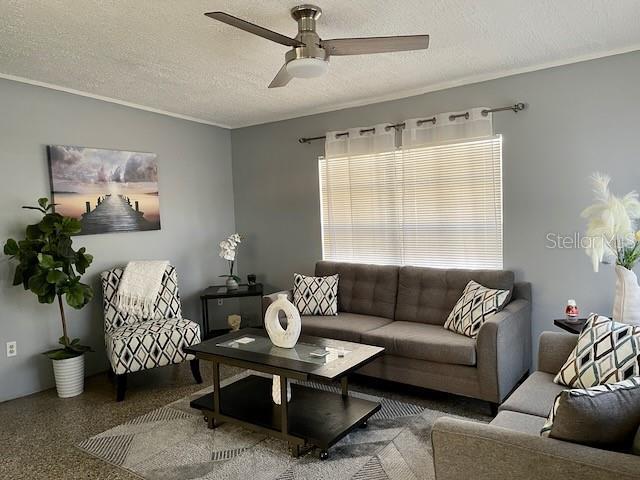 living room featuring a textured ceiling, speckled floor, and a ceiling fan