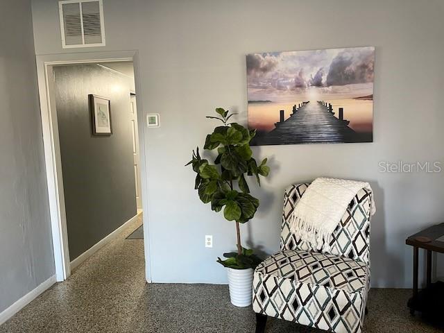 living area featuring speckled floor, baseboards, and visible vents