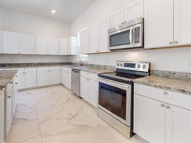 kitchen with marble finish floor, a sink, light stone counters, stainless steel appliances, and white cabinets