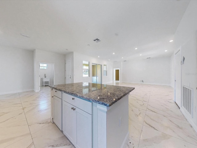 kitchen with dark stone countertops, visible vents, a kitchen island, and marble finish floor