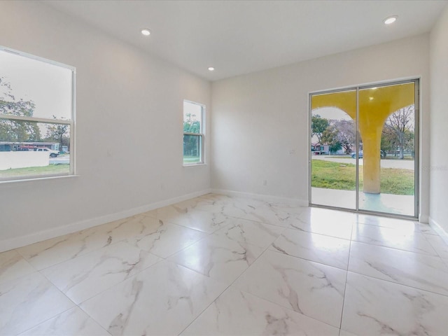 empty room featuring recessed lighting, marble finish floor, and baseboards