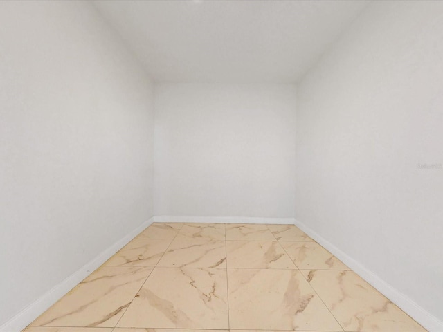 spare room featuring baseboards and marble finish floor