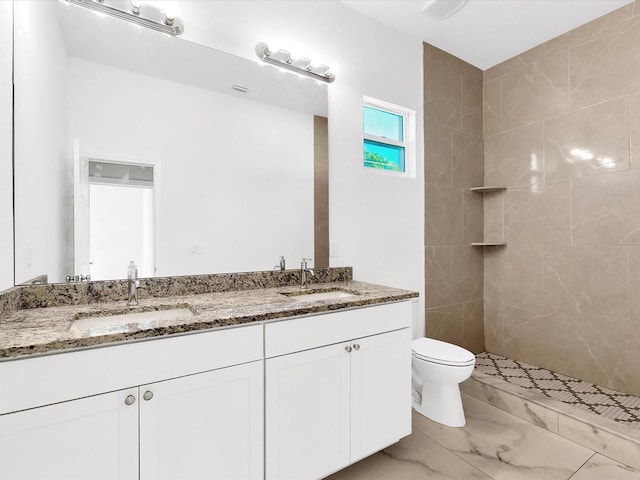 full bathroom with double vanity, toilet, a tile shower, and a sink