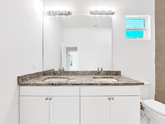 full bath with a sink, toilet, and double vanity