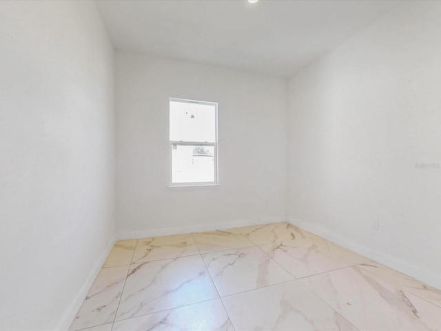 spare room with baseboards and marble finish floor