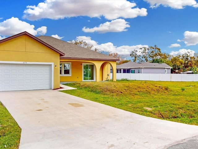 view of front facade with stucco siding, a front lawn, and fence