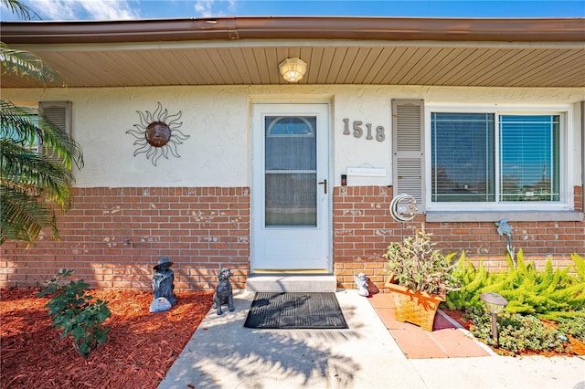 entrance to property featuring stucco siding and brick siding