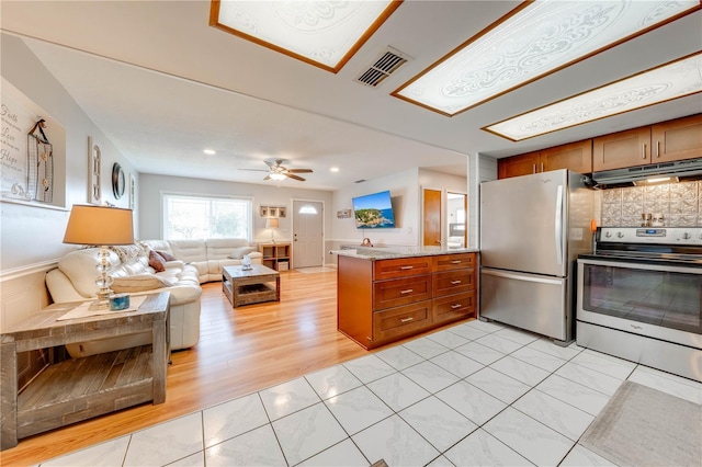 kitchen with under cabinet range hood, stainless steel appliances, brown cabinets, and visible vents