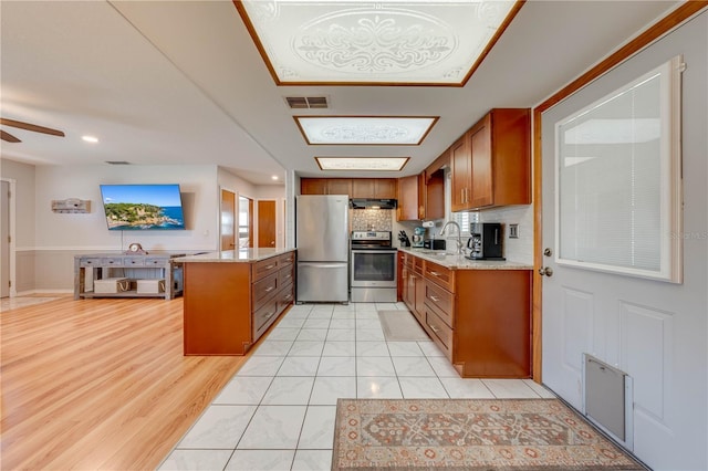 kitchen featuring a sink, stainless steel appliances, brown cabinets, and visible vents