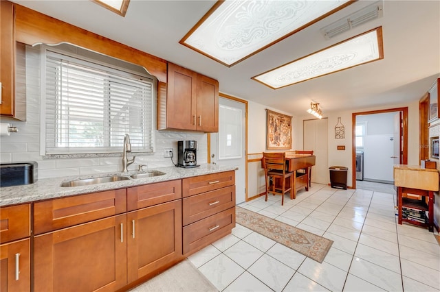 kitchen with visible vents, backsplash, a sink, brown cabinets, and a wealth of natural light