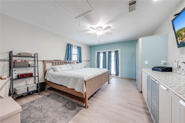 bedroom with attic access, a ceiling fan, visible vents, and light wood-type flooring