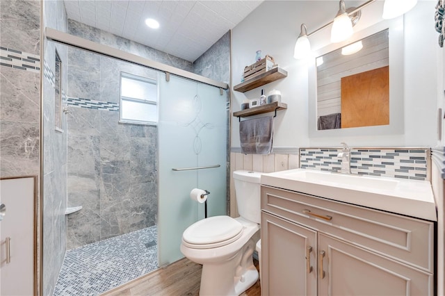 full bath with toilet, wood finished floors, vanity, and a tile shower