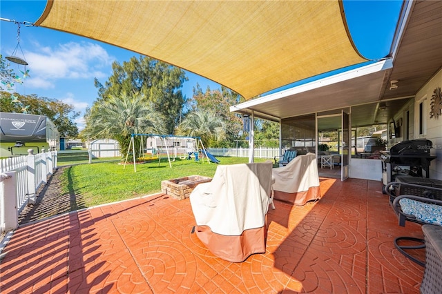 view of patio with grilling area, a playground, a shed, a fenced backyard, and a sunroom