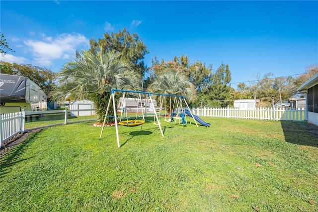 view of yard with an outbuilding, a shed, a playground, and a fenced backyard