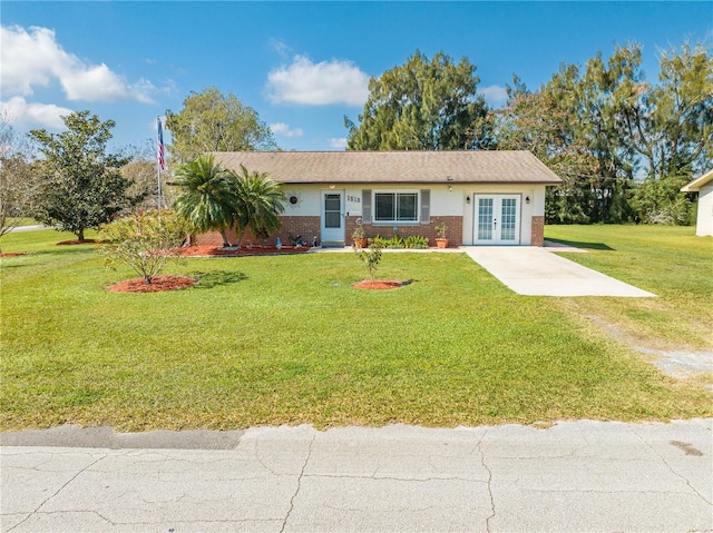 ranch-style house featuring a front lawn, french doors, brick siding, and driveway