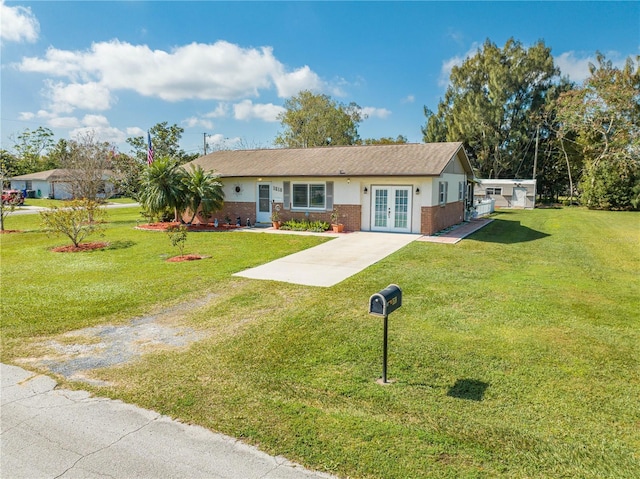 ranch-style home featuring brick siding, french doors, driveway, and a front yard