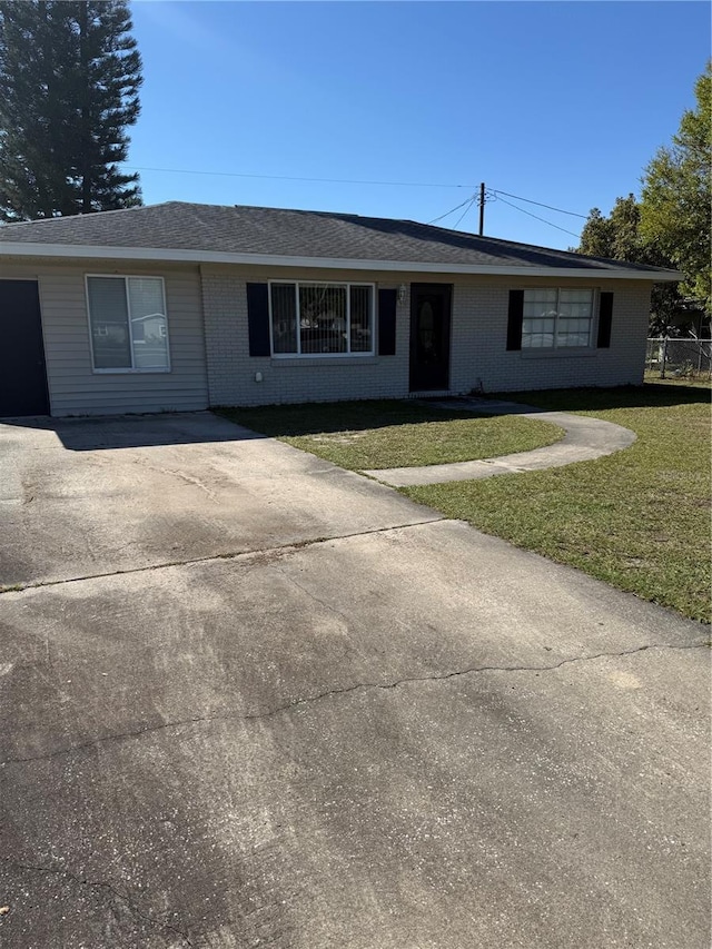 single story home featuring brick siding, concrete driveway, and a front lawn