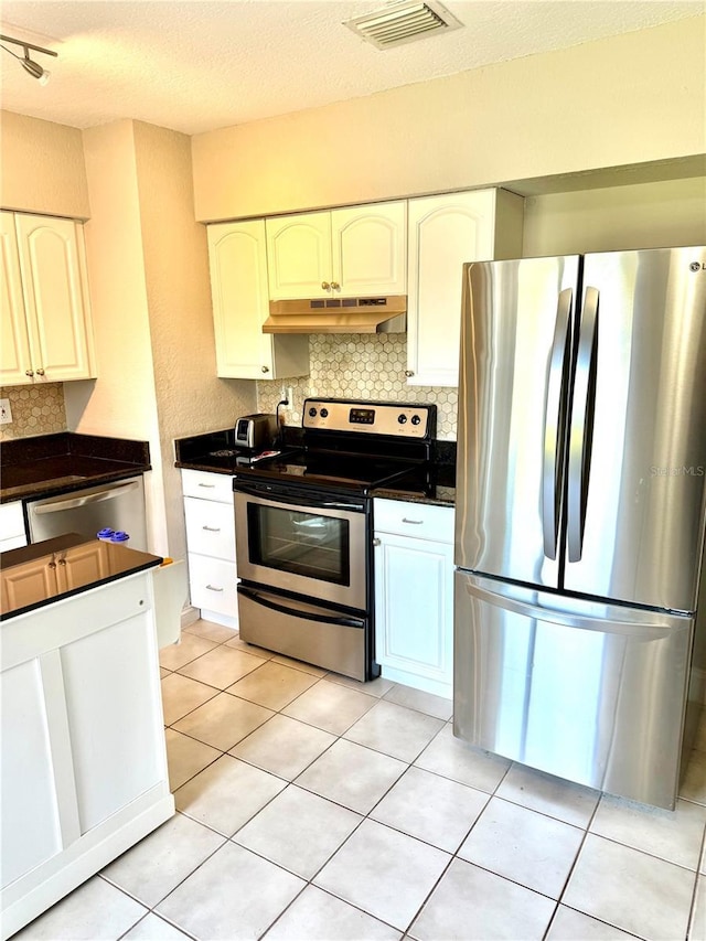 kitchen with visible vents, under cabinet range hood, appliances with stainless steel finishes, dark countertops, and backsplash