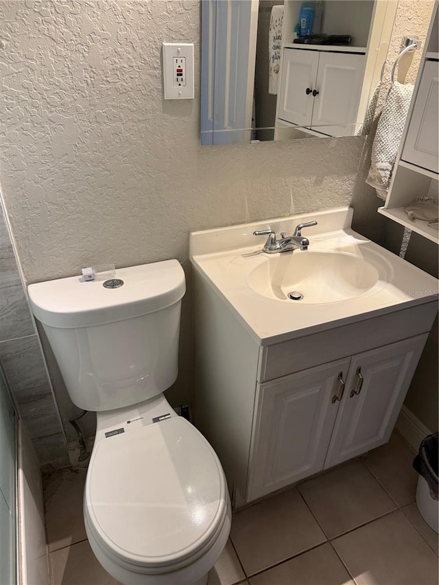 bathroom featuring toilet, vanity, and a textured wall