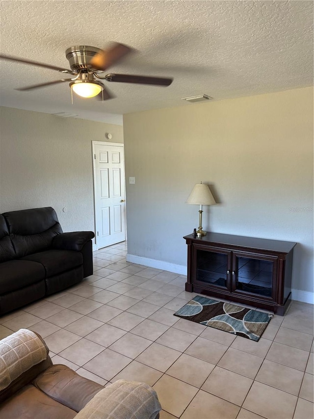 living room with light tile patterned floors, baseboards, a textured ceiling, and ceiling fan