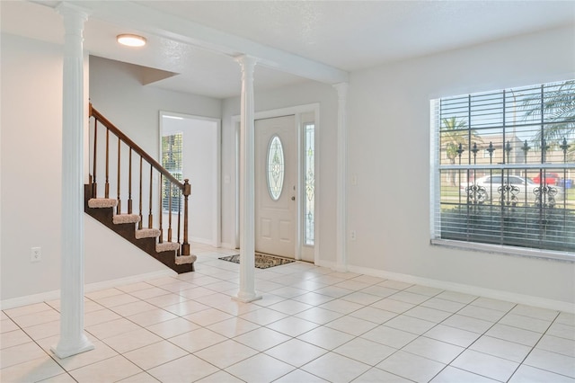 entrance foyer featuring light tile patterned floors, baseboards, and ornate columns