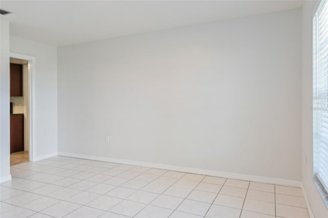 spare room with light tile patterned floors, visible vents, and baseboards