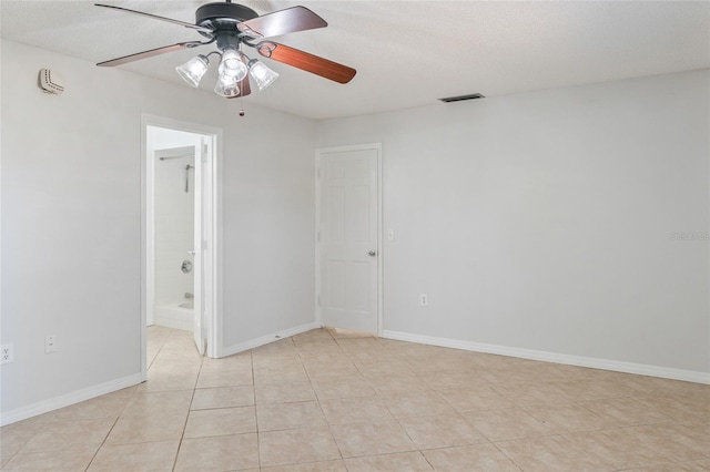 empty room featuring visible vents, ceiling fan, baseboards, light tile patterned floors, and a textured ceiling