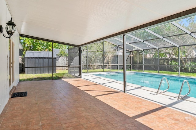 outdoor pool featuring glass enclosure, a fenced backyard, and a patio area