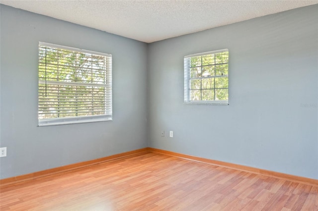 spare room featuring wood finished floors, baseboards, and a textured ceiling