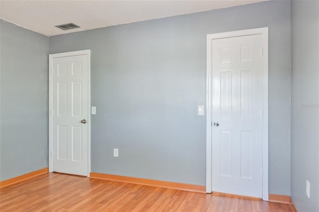 unfurnished room with visible vents, baseboards, light wood-style floors, and a textured ceiling