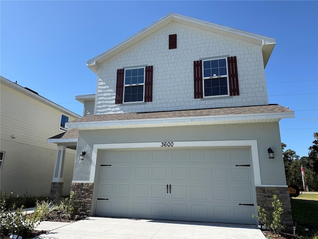 traditional home with driveway, stucco siding, a shingled roof, a garage, and stone siding