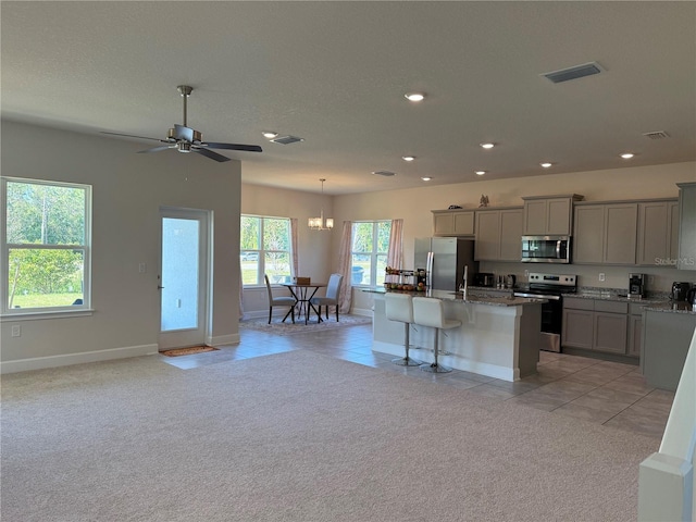 kitchen featuring visible vents, light colored carpet, gray cabinetry, and stainless steel appliances