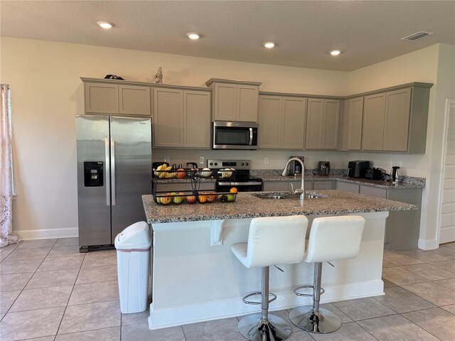 kitchen with gray cabinets, appliances with stainless steel finishes, and dark stone counters