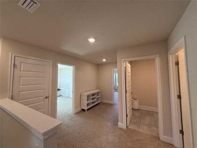 hallway featuring visible vents, light carpet, recessed lighting, light tile patterned floors, and baseboards