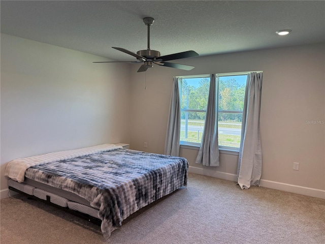 carpeted bedroom with ceiling fan, a textured ceiling, and baseboards