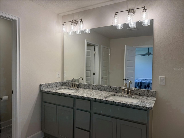 ensuite bathroom with double vanity, connected bathroom, a textured ceiling, and a sink